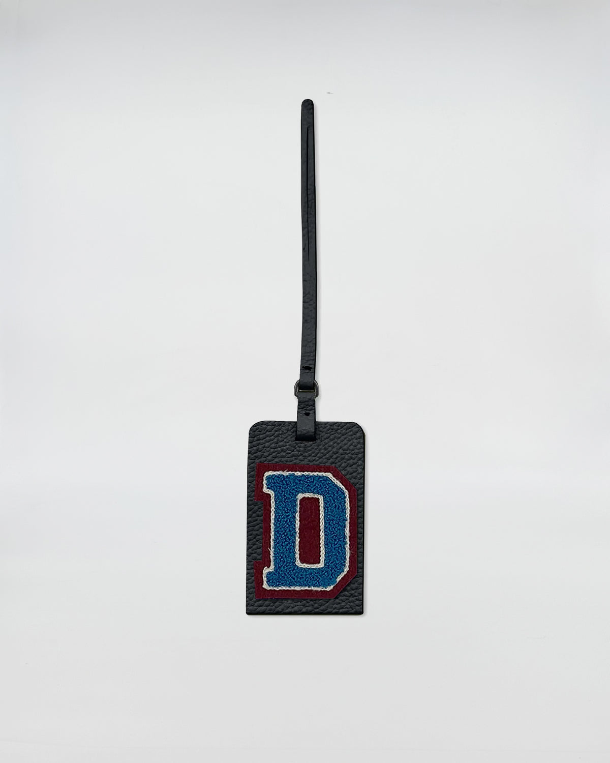 Charm personalizzato patch con lettera D in ricamo su accessorio in pelle rettangolare.