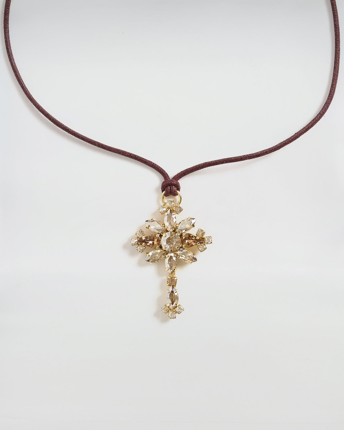 Collana Dori con ciondolo a croce in cristallo e nastro color cuoio, design elegante e sofisticato.