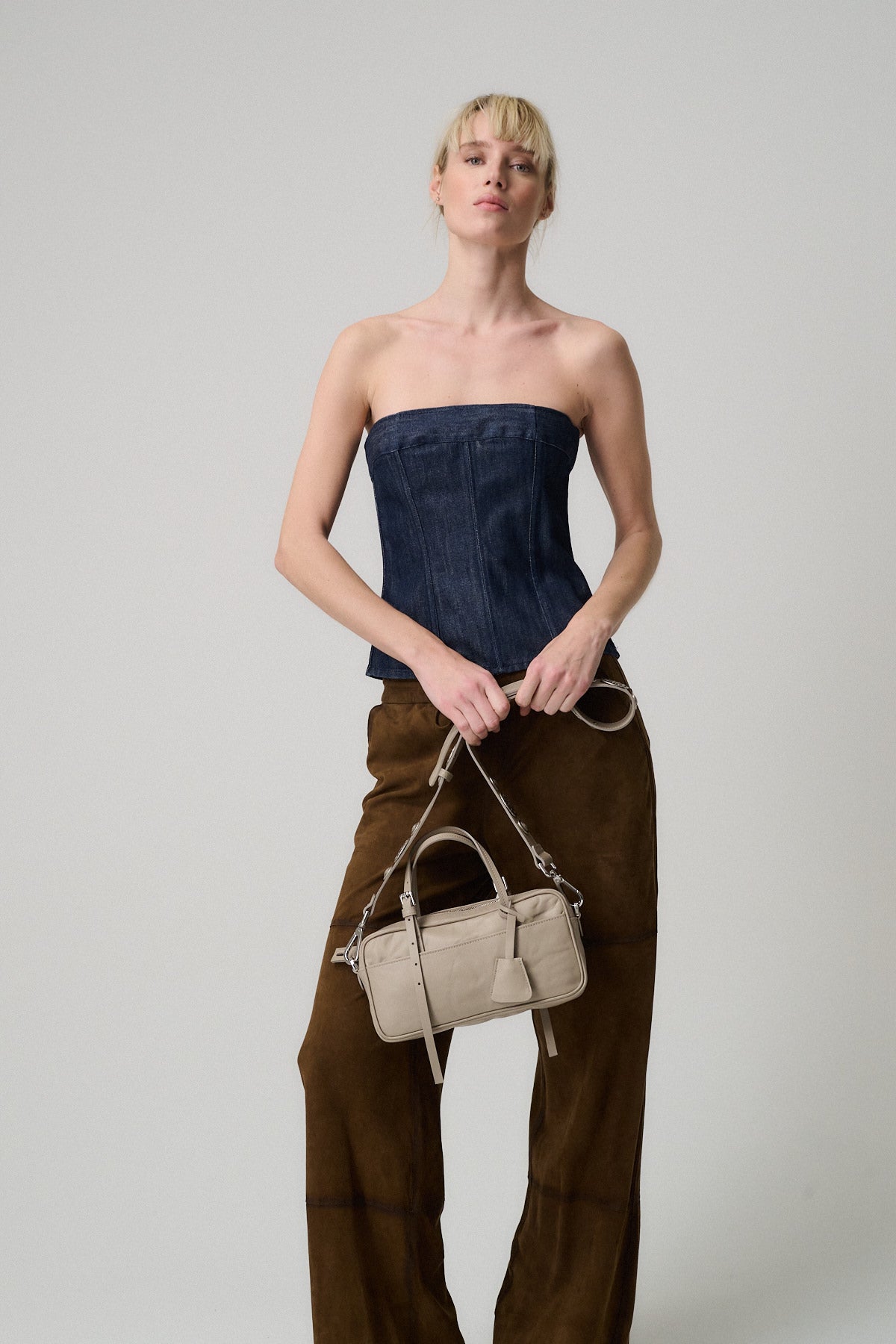 Modella che indossa un top senza spalline, mentre tiene la borsa ASIA VITELLO LAVATO TRACOLLA ROCK.