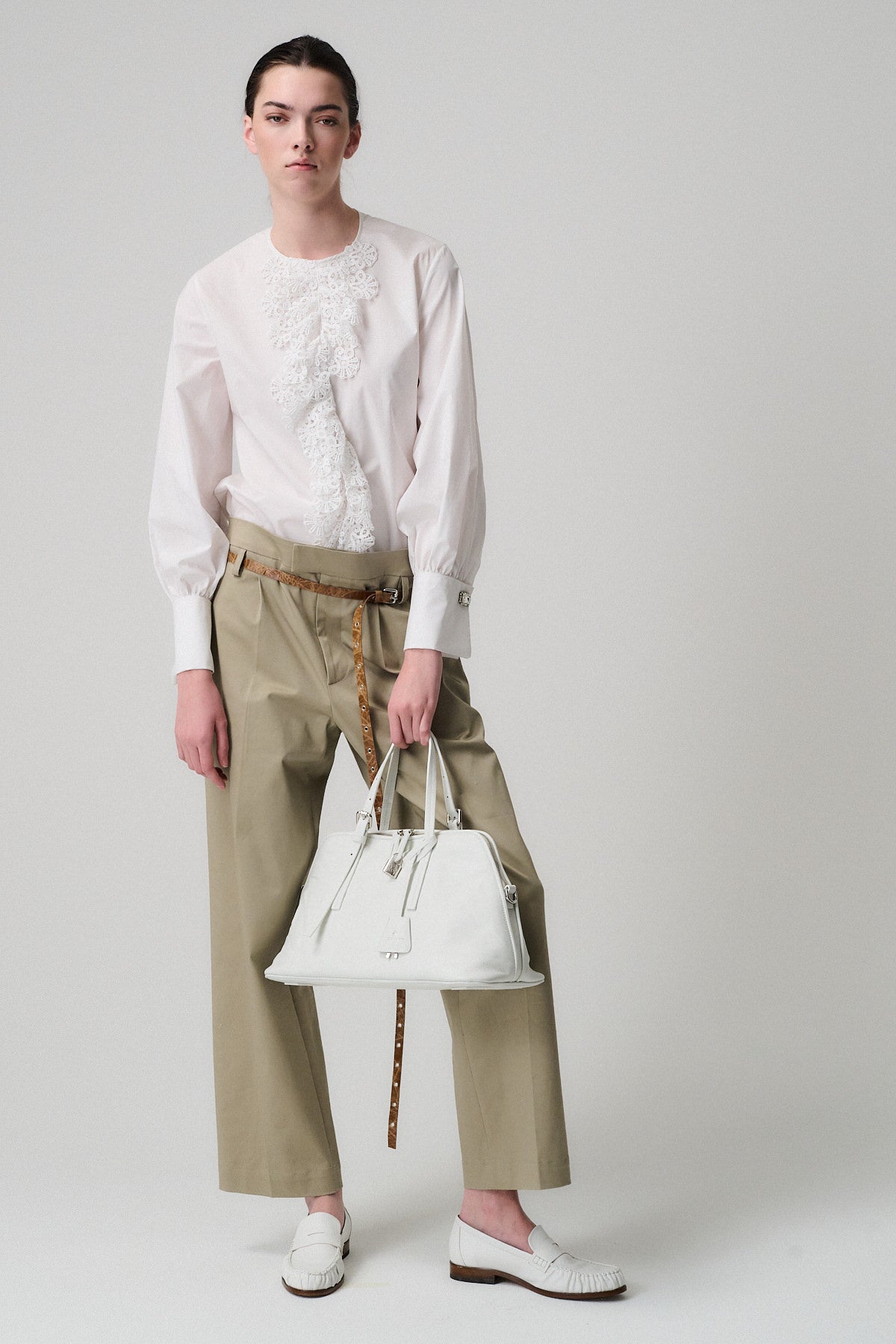 Modella con camicia bianca e pantaloni beige, tiene in mano la borsa Bowling Vitello Lavato.