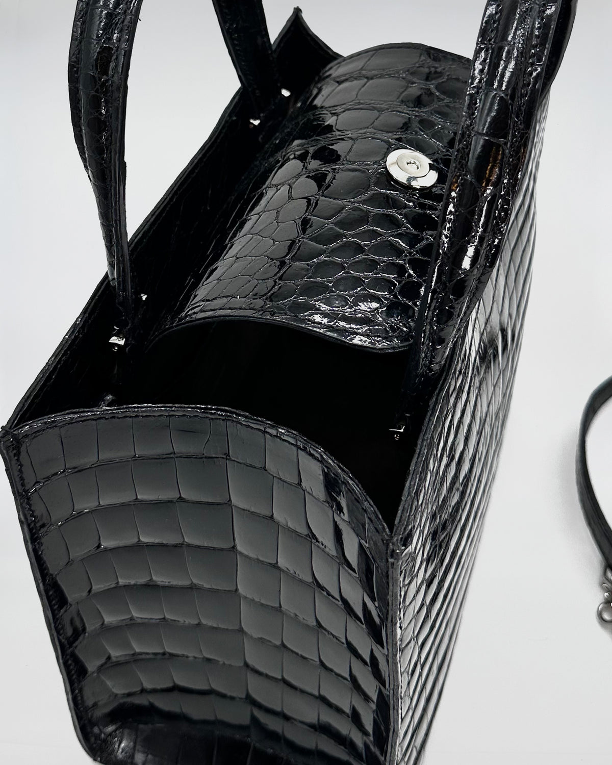 Close-up of the Matilda XS Cocco Recycle handbag in black crocodile-embossed leather with magnetic closure.