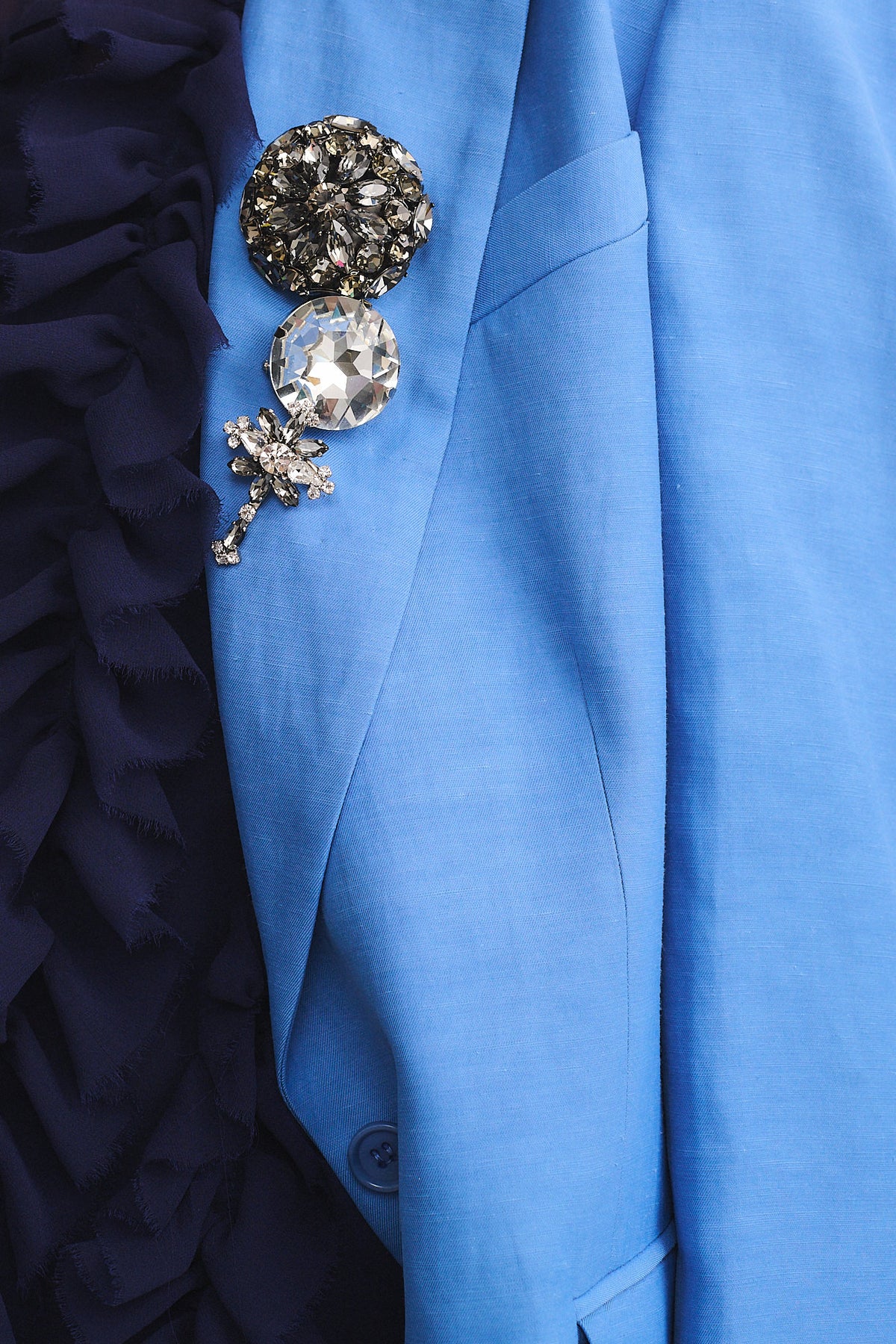 SPILLA MAXI ROUND CRISTALL on a blue jacket, featuring sparkling crystals that enhance elegance.