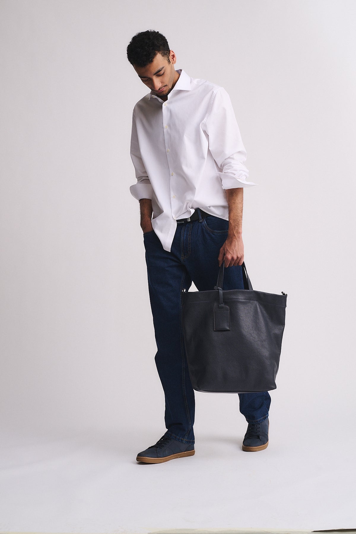 Modello che indossa la borsa FORD in pelle, abbinata a camicia bianca e jeans scuri per un look sofisticato.