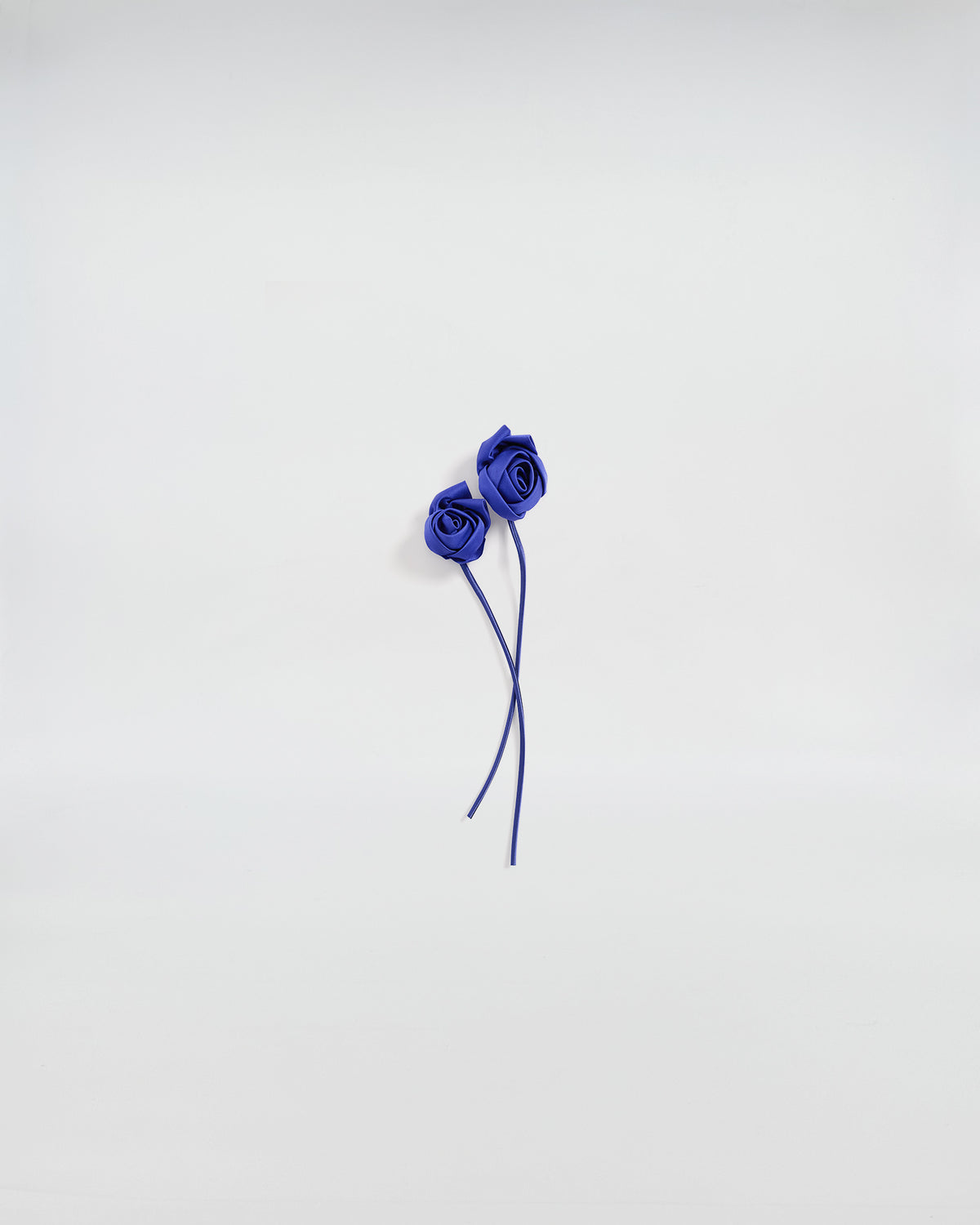 Boccioli di rosa in raso blu, accessorio elegante per giacche e abiti, design artigianale e romantico.