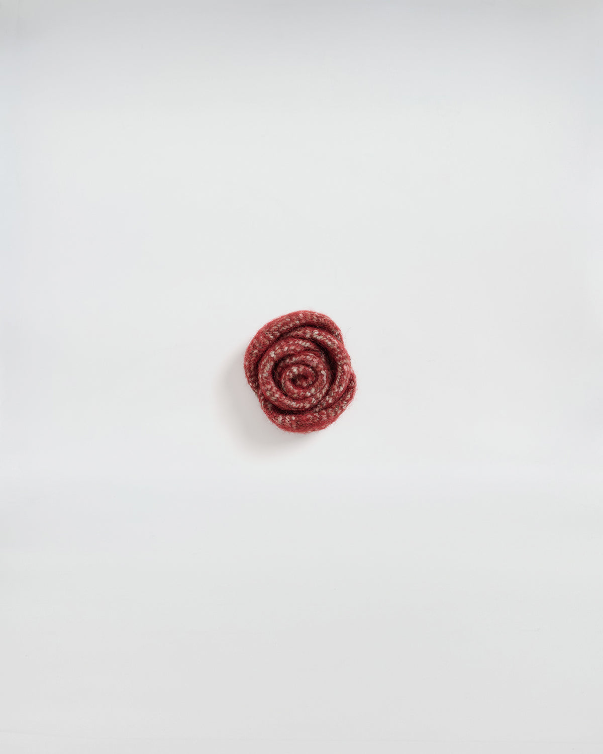 Spilla rosa in lana, accessorio elegante e contemporaneo, perfetto per giacche e cappotti.