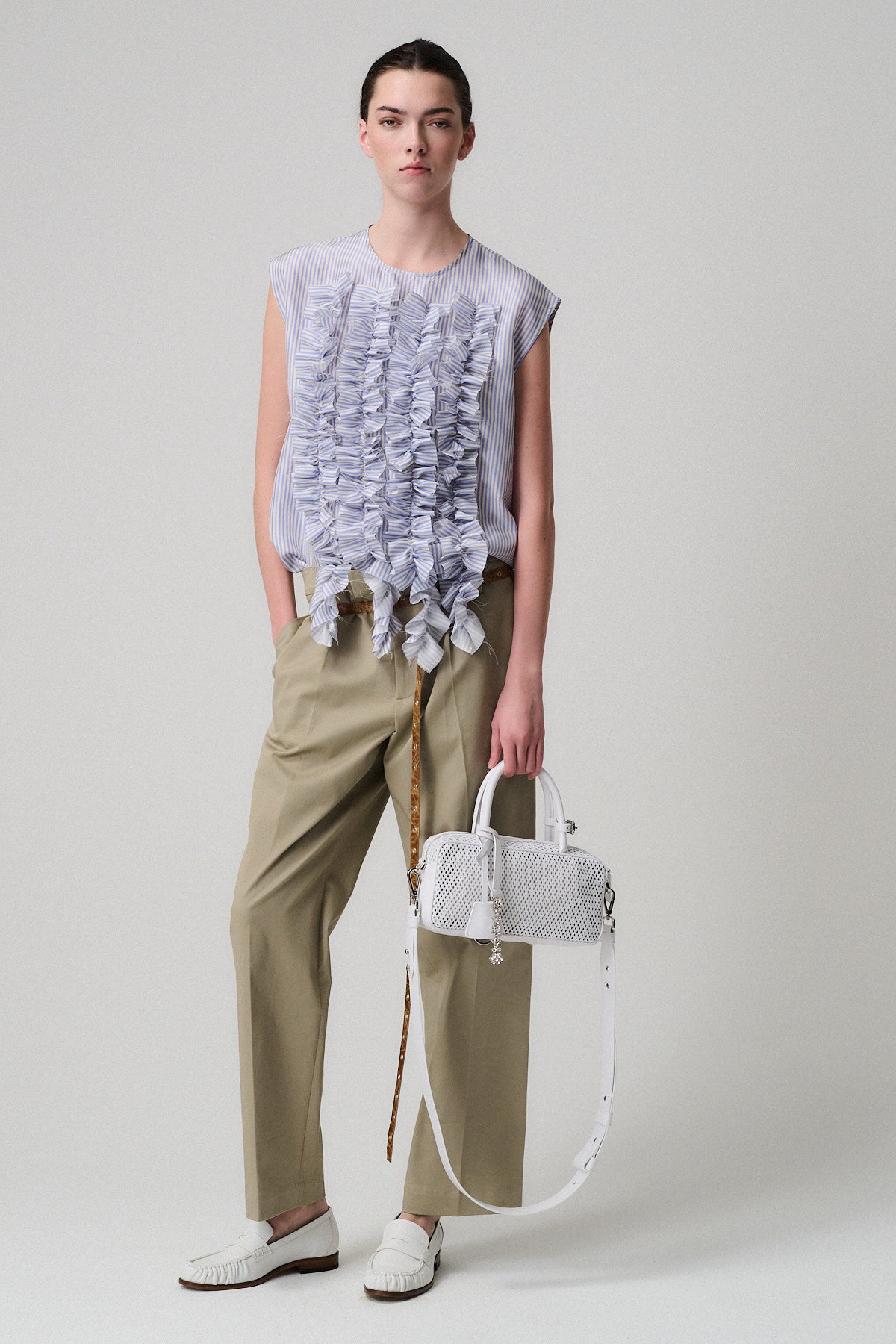 Modella che indossa un top con rouches accanto a una borsa ASIA VITELLO FORATO in pelle forata.