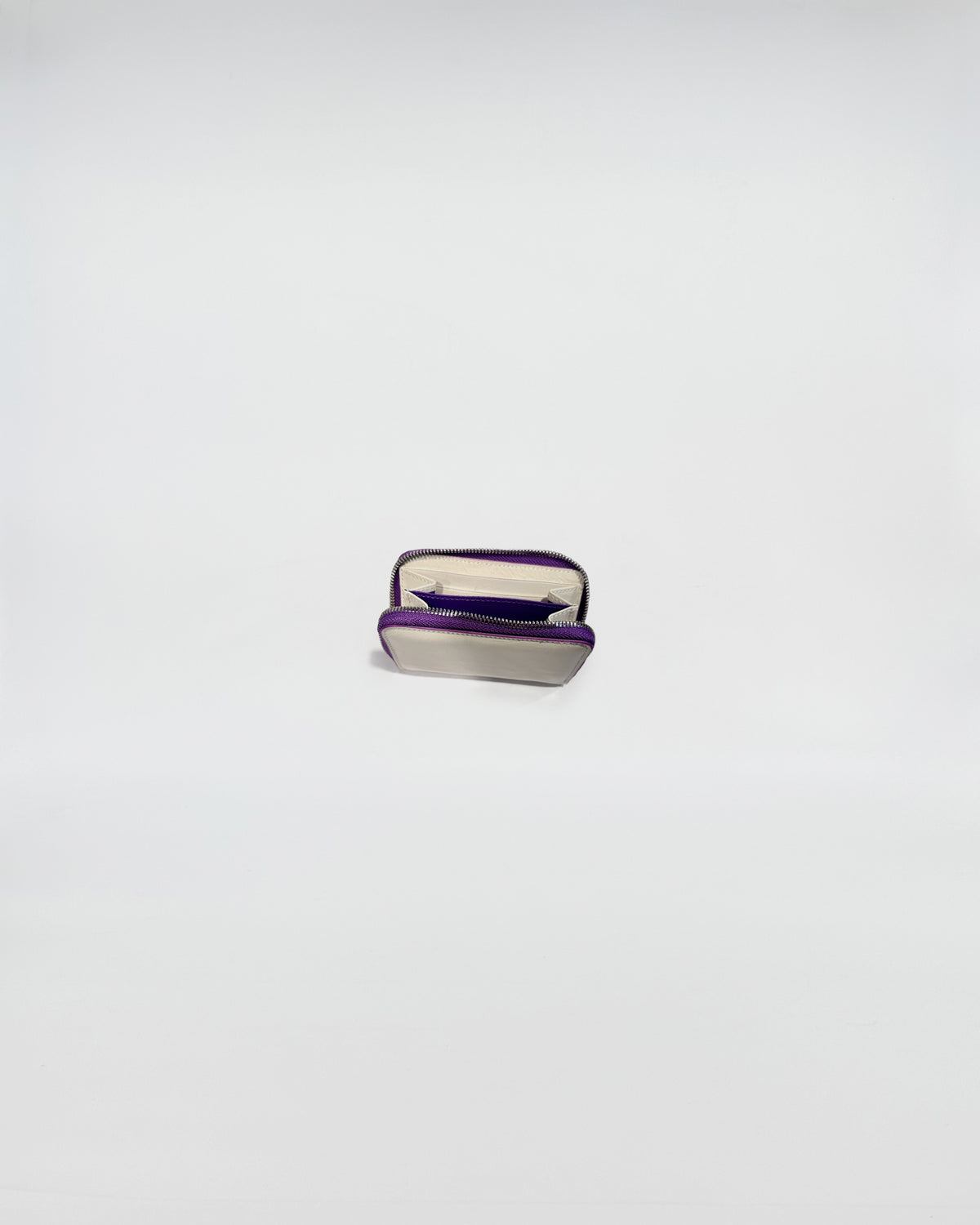 Portafoglio Zip Mini aperto, mostra interni in pelle e chiusura con zip viola, design sofisticato.
