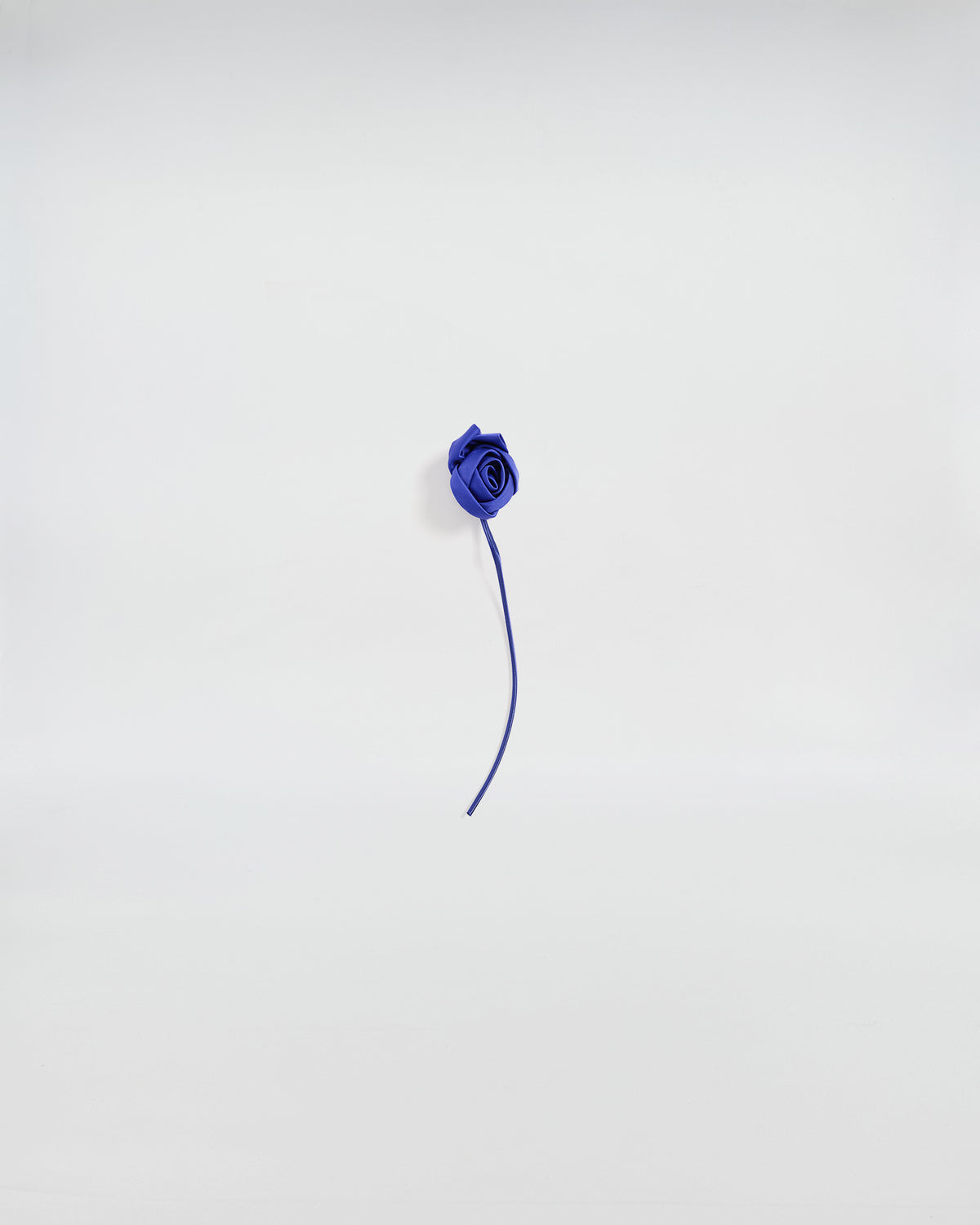 Elegante spilla con bocciolo di rosa in raso blu, dettaglio artigianale per accessori distintivi.